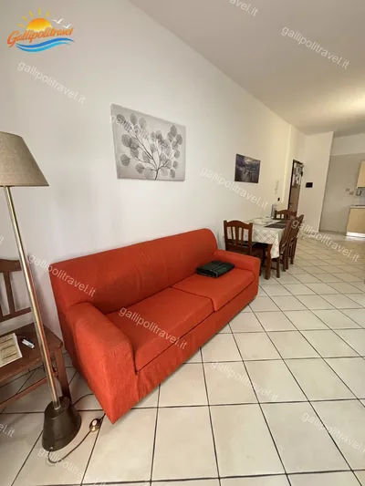Soggiorno divano rosso lampada piantana, trilocale B2/3 al Residence Rosa Virginia, Gallipoli