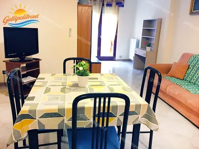 Soggiorno tavolo tovaglia gialla divano, trilocale H2/2 al Residence Rosa Virginia, Gallipoli